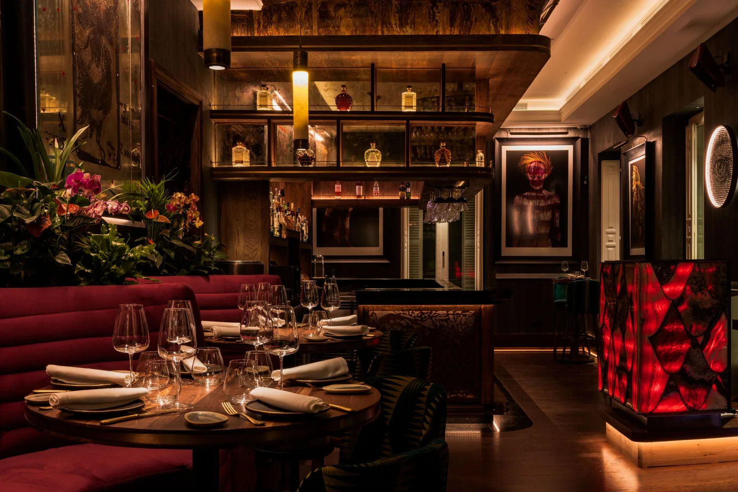 La barra de Abya con botellas iluminadas y sofás de terciopelo rojo