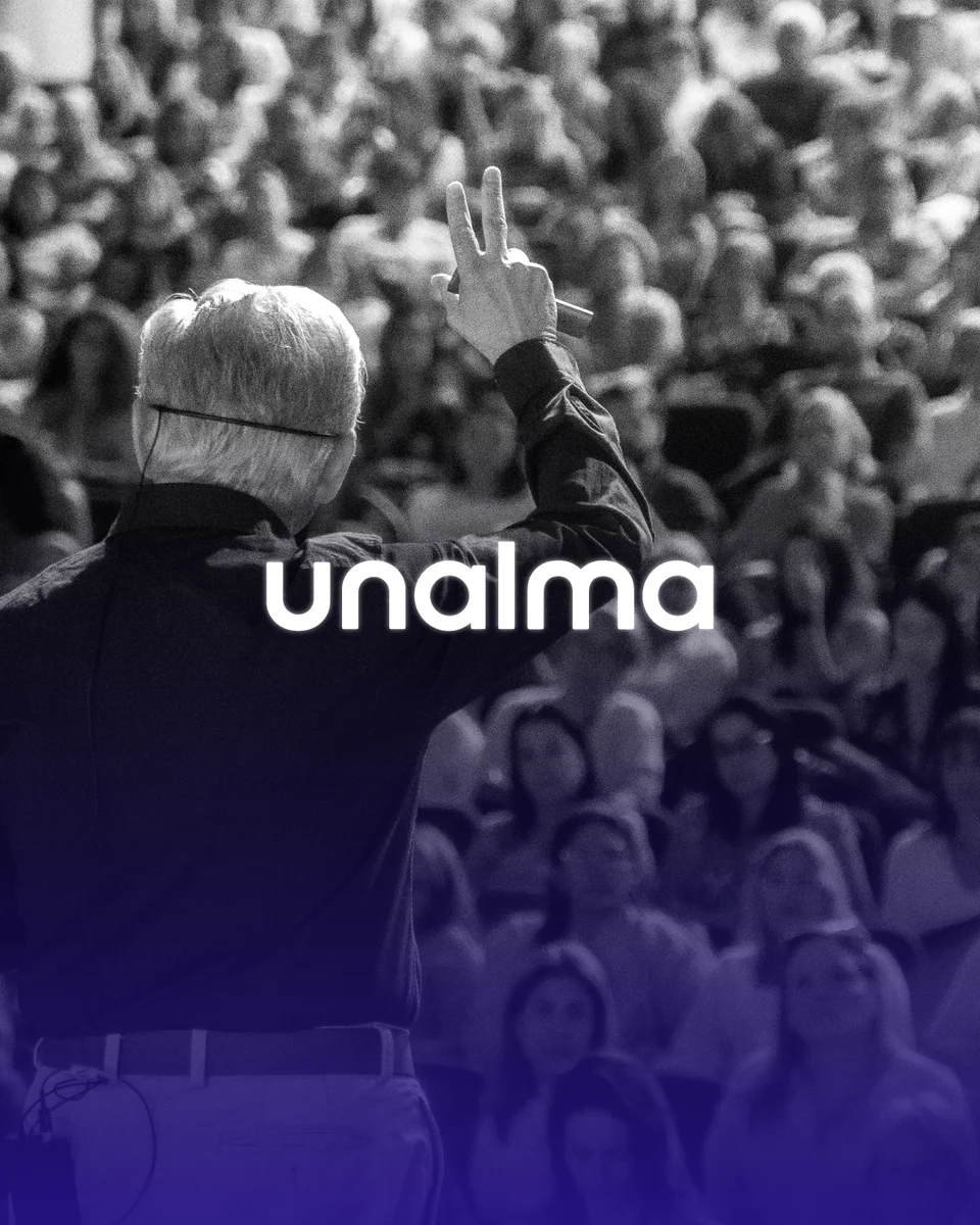 Logotipo de Unalma sobre la foto de un conferencista frente a un auditorio lleno, con degradado violeta